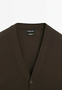 Brun merinoull cardigan med djup V-hals, enkel knappstängning och slät textur. Logotyp synlig inuti halsringningen.