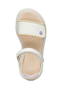 Sandalia blanca con plantilla texturizada, correa ajustable y un adorno circular con el logo. Presenta detalles en amarillo claro y azul en la parte superior.