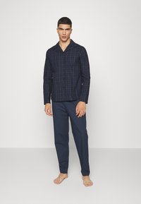 Conjunto de pijama a cuadros en color navy que incluye una camisa de botones de manga larga con cuello y pantalones de pierna recta. Tejido suave con una textura lisa.