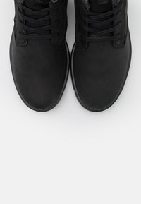 Zapatos negros con una parte superior de cuero liso, punta redondeada y cordones. El diseño presenta un interior acolchado y una lengüeta texturizada.
