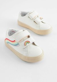 Hvide lædersneakers med to velcrolukninger, der har et regnbuebølge-mønster på siden og en farverig regnbueaccent nær stroppen.