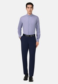 Ljusblå och vitrandig skjorta med spetsig krage, i kombination med skräddarsydda marinblåa byxor och svarta läderskor, med ett svart bälte.