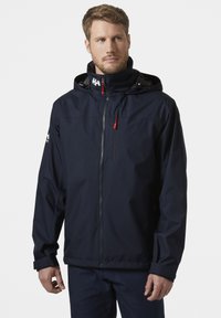 Navyblauwe waterdichte jas met een capuchon, ritssluiting aan de voorkant, rode ritsaccenten, verstelbare manchetten en logo op de schouder.