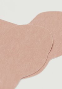 Náplasti v tělové barvě s hladkým povrchem, s kulatými okraji. Materiál se zdá být tenký a flexibilní, vhodný pro aplikaci na pleť.