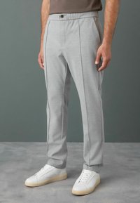 Light gray athletic-style pants with a smooth texture, featuring contrasting dark seam accents, a button closure, and a tapered fit.