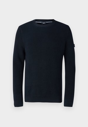 Marinblå stickad tröja med ribbat mönster, rundad hals, långa ärmar och en subtil logopatch på vänster ärm.