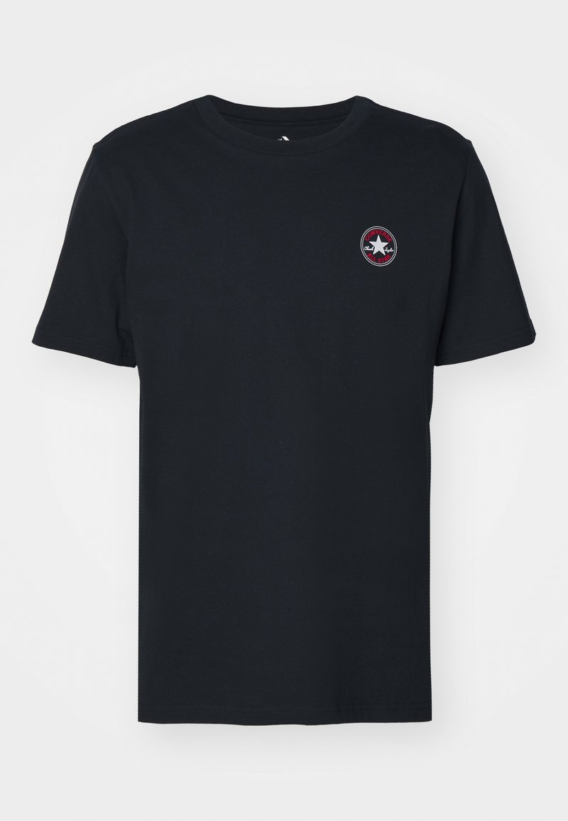 T-shirt noir à manches courtes et col rond avec petit logo rond Converse en blanc et rouge sur le côté gauche de la poitrine.