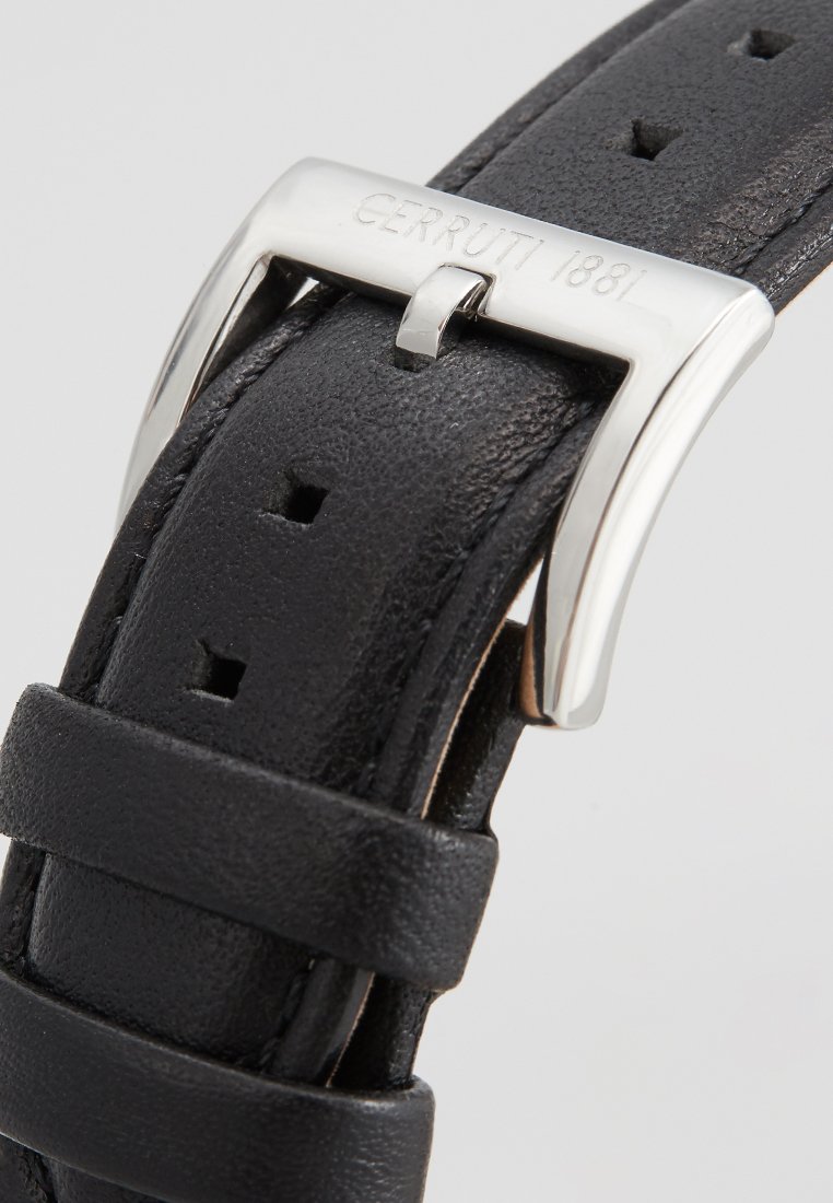 Bracelet de montre en cuir noir avec une boucle en métal argenté portant l'inscription gravée "CERRUTI 1881." Surface texturée et plusieurs trous d'ajustement.