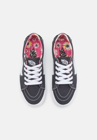 Sneakers Vans nere con lacci e cuciture bianche, striscia laterale bianca e fodera interna rosa con un motivo a margherite gialle e bianche.