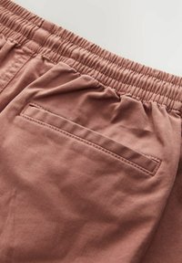 Lichtroze shorts van zachte stof, met een elastische tailleband en een enkele achterzak met een gestikt randje.
