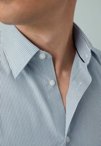Hellblau gestreiftes Hemd mit Kentkragen, ausgestattet mit weißen Knöpfen und einer glatten Baumwolltextur. Der Fokus liegt auf dem Kragen und den Stoffdetails.