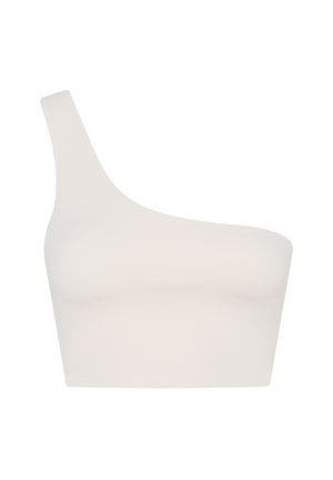 Valges tanktopis ja mustades pükstes naine tasakaalus kätekõverduses, põlved kõverdatud, helel taustal.