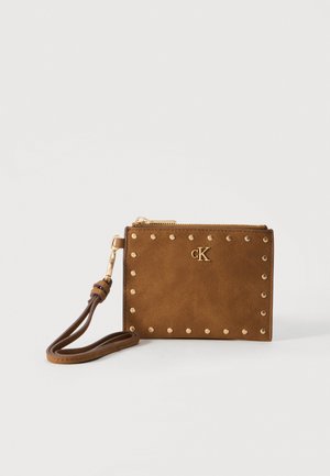 Petit porte-poignet en cuir marron avec bordure de clous dorés, fermeture éclair dorée, logo CK et une lanière bouclée sur fond blanc.