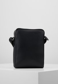 Borsa rettangolare in pelle nera con superficie testurizzata; dotata di una chiusura superiore a zip e di una maniglia laterale per un facile trasporto.