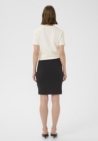 Bluză albă cu mânecă scurtă, asortată cu o fustă-pennel neagră, cu o textură netedă și un design minim. Linii simple și curate pe tot parcursul.