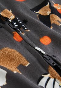 Grijze stof met patronen van dieren en pompoenen, met een rits die in het midden loopt. Zichtbare dieren zijn onder anderen beren en koeien.
