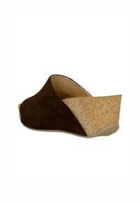 Sandale en cuir suédé marron avec un talon en liège. Le design présente une ouverture à l'avant et un dos courbé, mettant en avant le confort et le soutien.