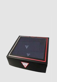 Berretto all'uncinetto blu scuro esposto in una scatola rettangolare nera con coperchio trasparente. Presenta un logo a triangolo e accenti rossi minimalisti.