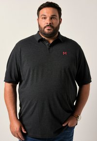 Tmavě šedý polo tričko s límečkem, krátkými rukávy, rovnou siluetou a malým červeným logem na levé straně. Měkká textilie.