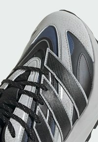 Sportliche Sneakers in einer Mischung aus Schwarz, Grau und blauen Materialien; verfügen über ein geschichtetes Design, strukturierte Akzente und schwarze Schnürsenkel.