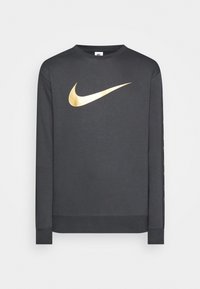 Šedá dlouhá mikina s dlouhým rukávem a zlatým logem Nike Swoosh na přední straně a textovými akcenty po straně. Měkká tkanina a žebrované manžety.
