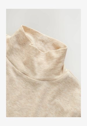 Beige soonikkoe kaelusega tipp, millel on pehme tekstuur, kõrge krae ja istuv siluett, rõhutades disaini lihtsust.