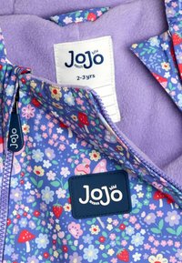 Lila Kinderjacke mit Reißverschluss, blumigen und fruchtigen Mustern, weicher fleecegefütterter Innenseite und einem gewebten Markenetikett. Die Größenangabe lautet "2-3 Jahre."