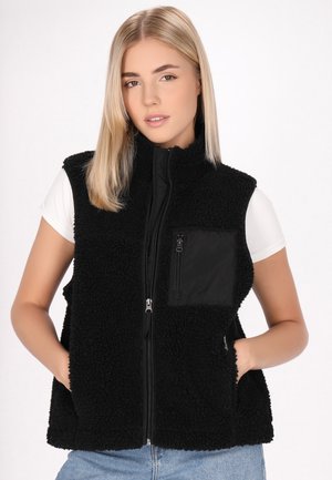 Gilet in pile nero con zip frontale, tasche laterali e tasca sul petto; presenta un'esterno textured e fluffy e un pannello nero liscio.