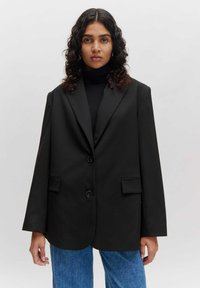Zwarte blazer van gladde stof, met een reverskraag, twee knopen en zijzakken. Oversized pasvorm met een gestructureerde silhouet.