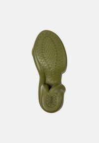 Green, flexible footwear sole with a textured pattern, oval shape, and cushioning features; includes logos and size indication.
