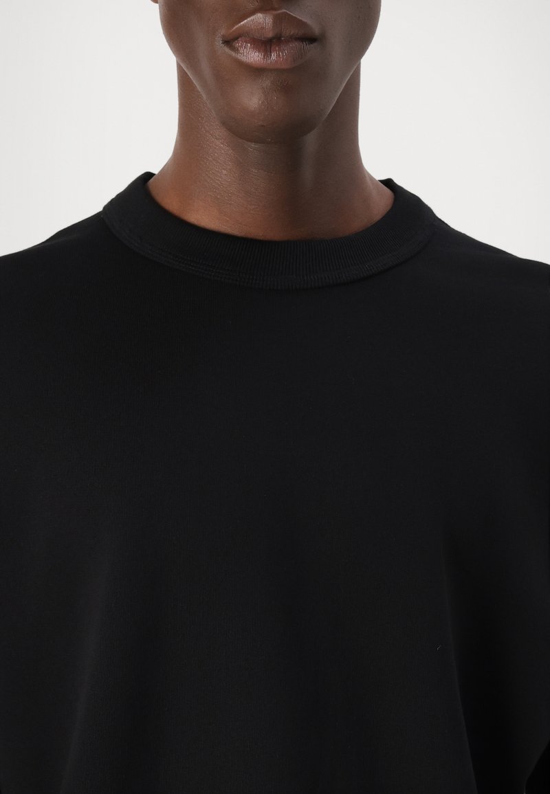 Czarny bawełniany sweatshirt z okrągłym dekoltem o gładkiej fakturze i prążkowanym wykończeniu, charakteryzujący się minimalistycznym designem oraz brakiem widocznych logo czy wzorów.