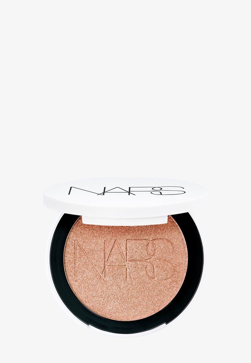 Highlighter NARS dans un boîtier rond, avec une formule scintillante rose doré à la texture douce, un couvercle blanc et une base noire.