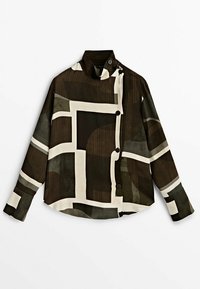 Chemise à manches longues boutonnée avec col montant et motif abstrait géométrique marron, noir et blanc, posée à plat sur fond blanc.