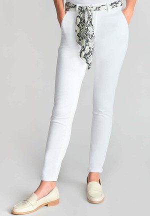White fitted pants with a snake print belt, smooth texture, featuring side pockets. Paired with light-colored loafers and a cropped top.