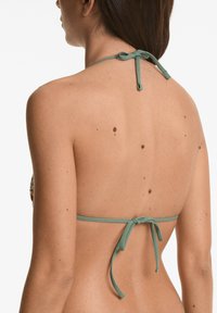 Grön halterneck-bikinitop med justerbara snörr. Slät tyg med en figursydd design. Sedd bakifrån, med en minimalistisk stil.