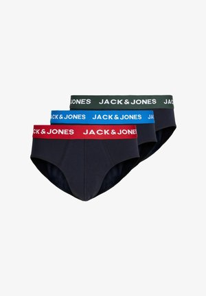 Ung muskuløs mand med kort blondt hår iført mørke trusser med en rød linning mærket Jack & Jones, stående mod en ensfarvet baggrund.