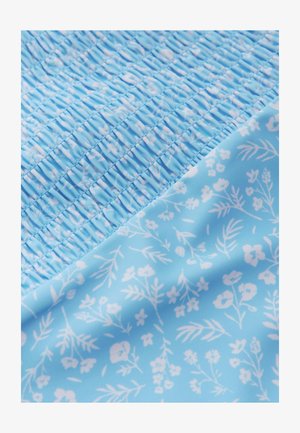 Tissu bleu avec une texture smockée d'un côté et un motif floral blanc de l'autre. Texture douce et lisse.