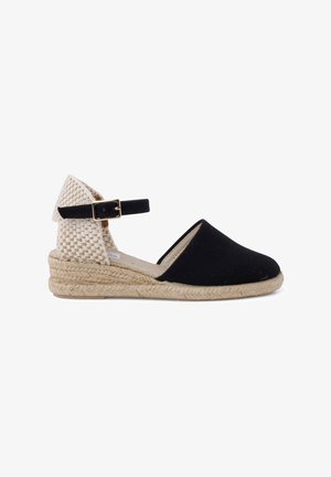 Černé plátěné espadrilky s tkaným béžovým zadním dílem, kotníkovým popruhem a jutu rope podešví. Nízká wedge konstrukce, styl na nazouvání a zaoblená špička.