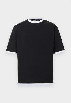 Camiseta negra de manga corta con ribetes blancos en el cuello, los extremos de las mangas y el dobladillo, mostrada sobre un fondo gris claro liso.