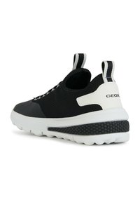 Zapatilla de malla negra con un acento blanco en el talón. Presenta una suela de goma texturizada y cordones elásticos, diseñada para la transpirabilidad y la comodidad.