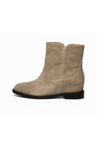 Beige mockaskinnankelboots med en strömlinjeformad design, låg svart klack och en vertikal sömdetalj på utsidan.