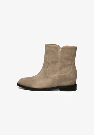 Stivali ankle in suede beige con un design snello, tacco nero basso e un dettaglio con cucitura verticale sul lato esterno.