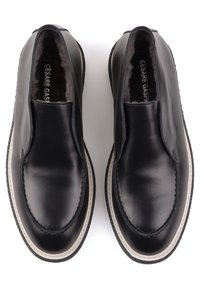 Paire de chaussures en cuir noir à enfiler avec semelles blanches et doublure en fourrure, vues de dessus.