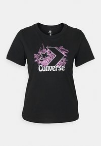 Svart bomulls t-shirt med en rosa grafisk design som visar tropisk lövverk och ordet "Converse" i vitt. Rund hals, korta ärmar.