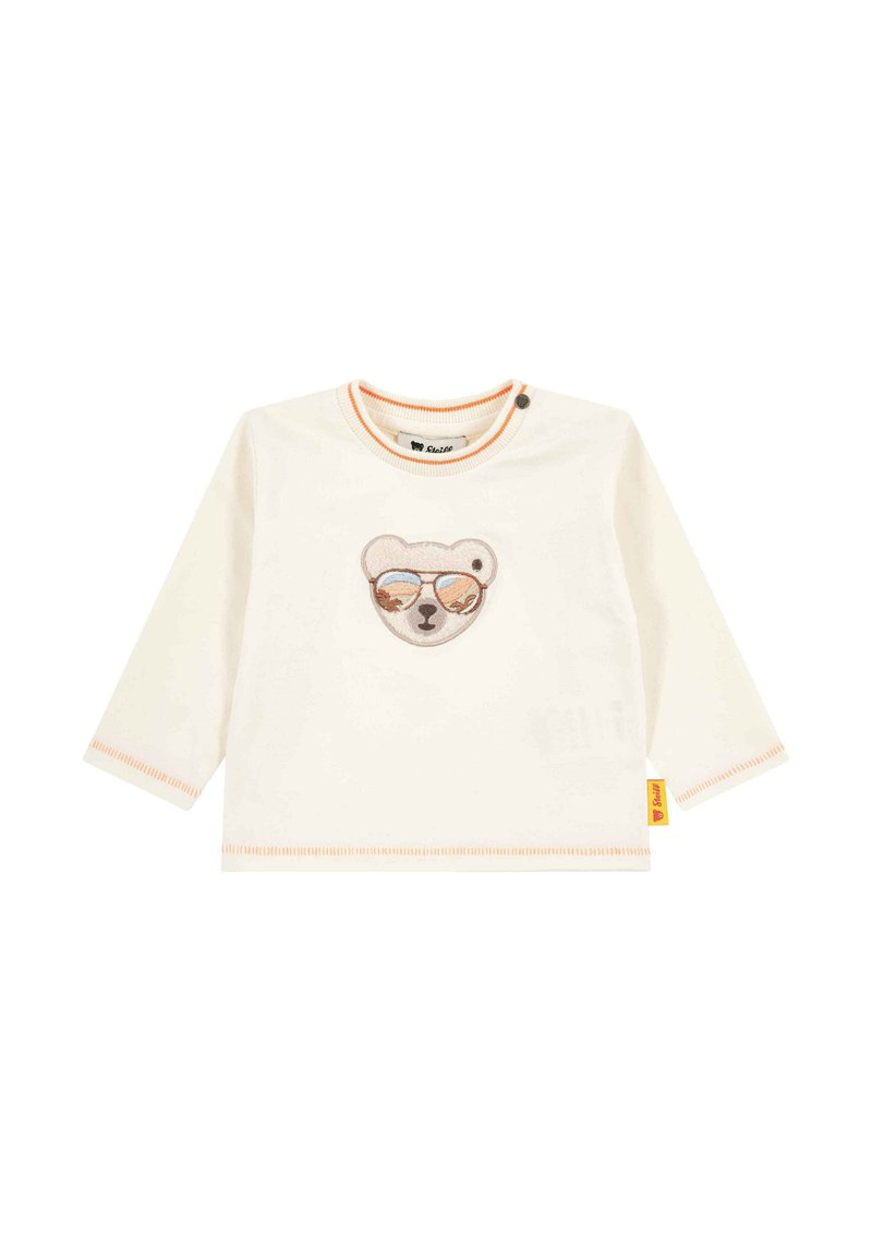 Chemise pour bébé à manches longues couleur crème avec des coutures orange et un visage d'ours portant des lunettes de soleil brodé sur la poitrine.