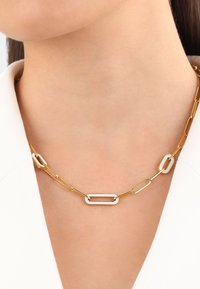 Un collar de cadena de oro presenta eslabones ovalados alargados con un eslabón rectangular más ancho, mostrando un acabado suave y pulido.