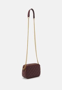 Burgundy kviltad lädercrossbody-väska med guld kedjestraps och dragkedjestängning, med en rektangulär form och slät yta.