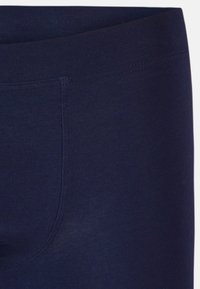 Navy blue leggings made of smooth and stretchy fabric. They feature a wide elastic waistband and flat seams for enhanced comfort. Ideal for active wear.