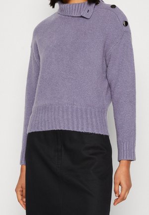 Jersey de punto lavanda con cuello alto acanalado, detalles de botones en el hombro, bajo y puños acanalados, combinado con una falda negra.