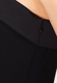 Černá sukně s hladkou texturou, přiléhavým střihem a pasem se zapínáním na malý knoflík. Jednoduchá a elegantní.